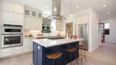kitchen with ceiling mounted range hood blue island and white cabinets