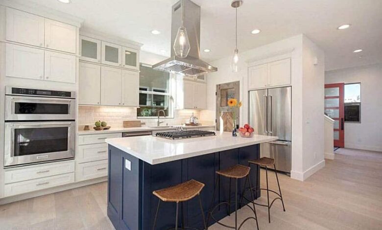 kitchen with ceiling mounted range hood blue island and white cabinets