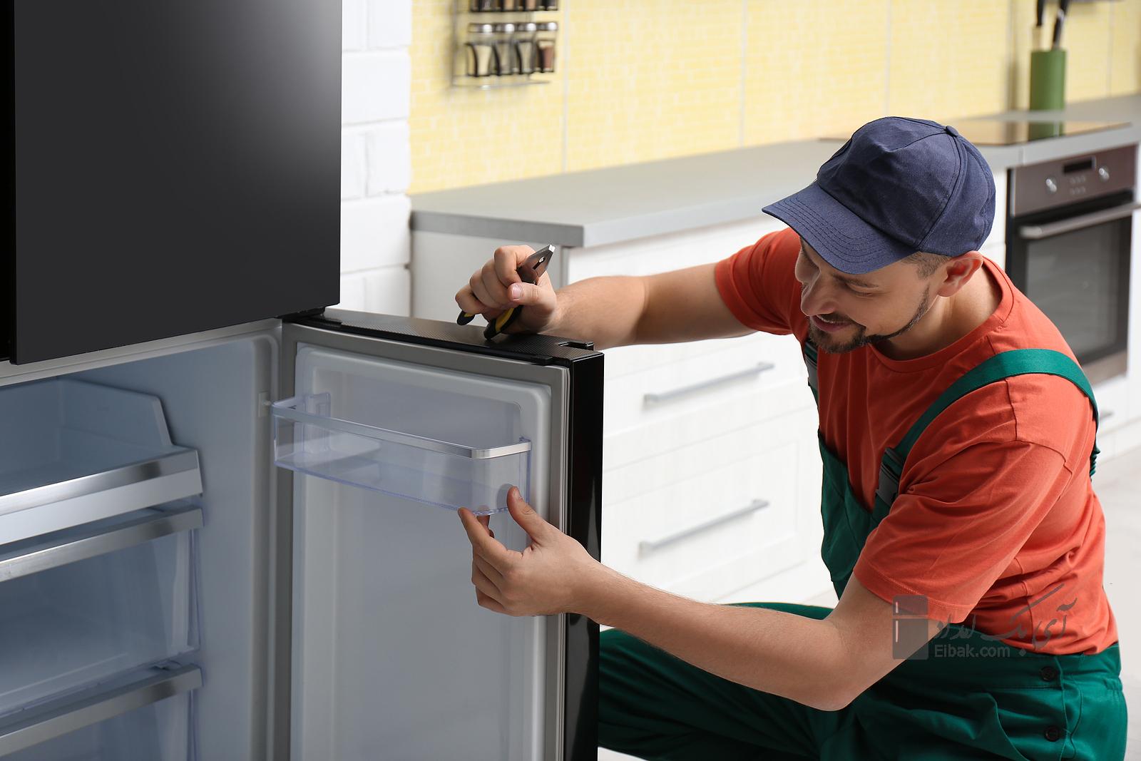 Male Appliance Technician With Pliers Repairing Refrigerator Indoors