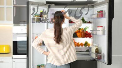Young woman near open refrigerator in kitchen back view 1